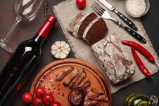 Sliced Grilled Pork Steaks With Bottle Of Wine, Wine Glass, Corkscrew, Knife, Fork, Black Bread, Cherry Tomatoes, Garlic, Onion Royalty Free Stock Photo