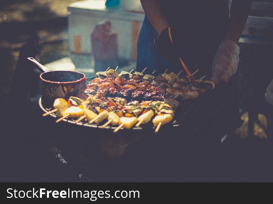 Preparation of barbecue, Grilled skewers on plate outdoor..Grilled shish kebab on metal skewer. Chef hands cooking roasted meat slices barbecue with lots of smoke. BBQ fresh beef chop slices. Traditional eastern dish on charcoal and flame, picnic, street food