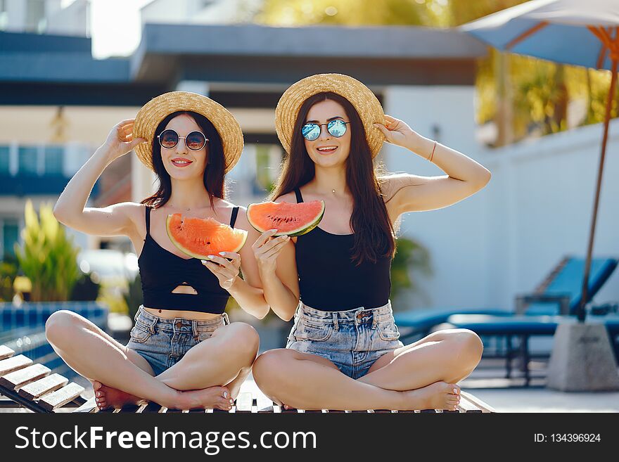 Two girls eating watermelon by the pool in Thailand