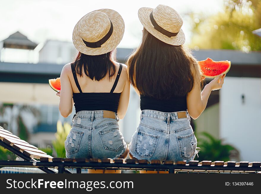 Two girls eating watermelon by the pool in Thailand