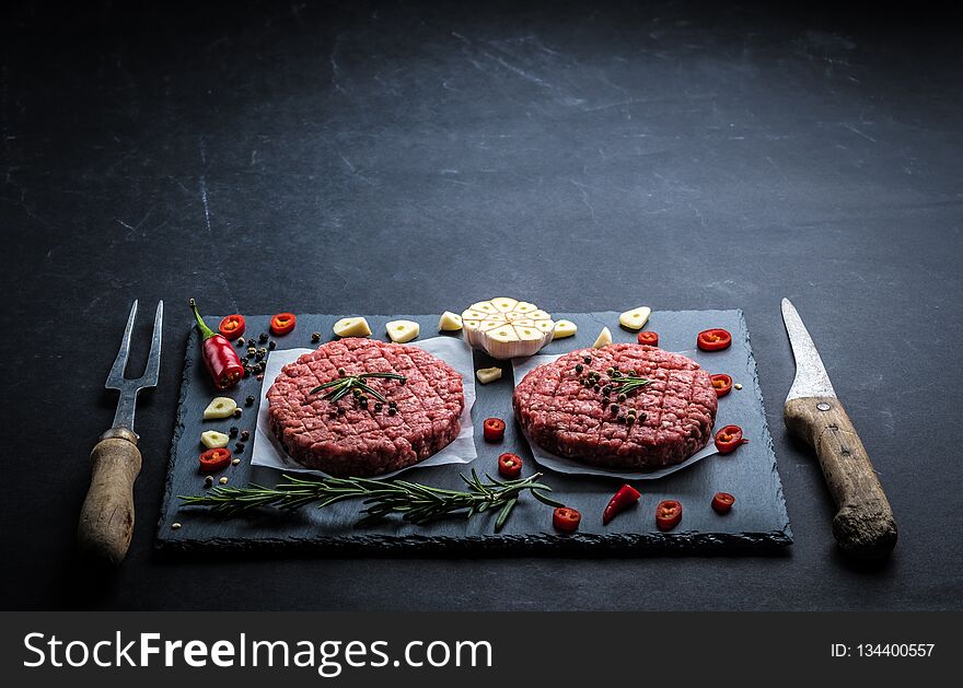 Raw cutlet of minced meat with ingredients on a dark cooking background. Raw cutlet of minced meat with ingredients on a dark cooking background