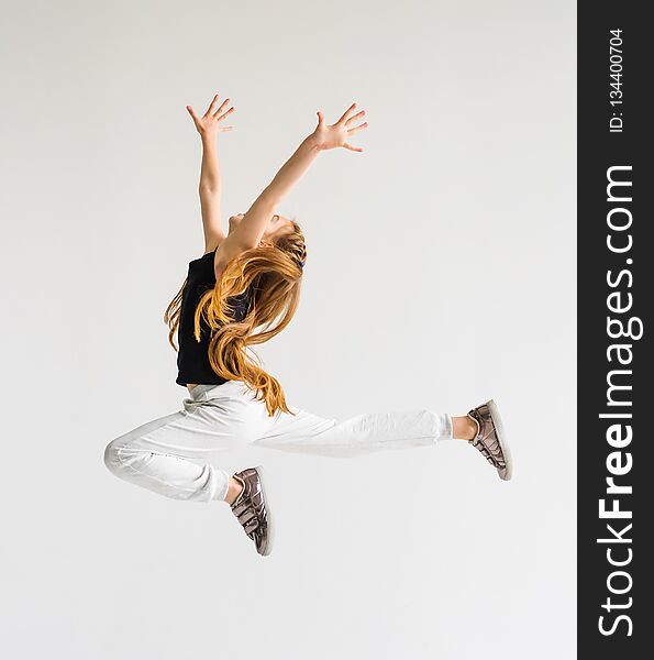 Excited young girl leaping in the air with her hands raised. Sport, training, dancing lifestyle. Excited young girl leaping in the air with her hands raised. Sport, training, dancing lifestyle.