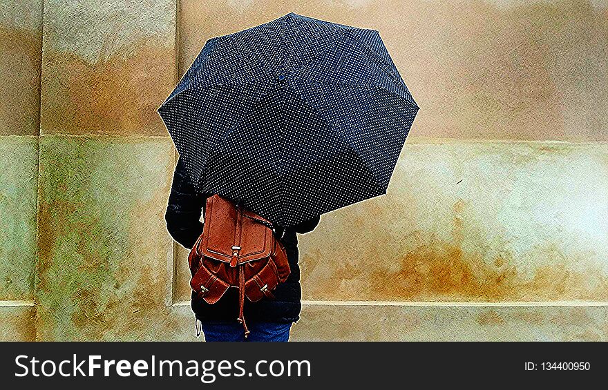 Beautiful girl with a brown leather backpack holding umbrella in the street on a rainy day - visiting Copenaghen