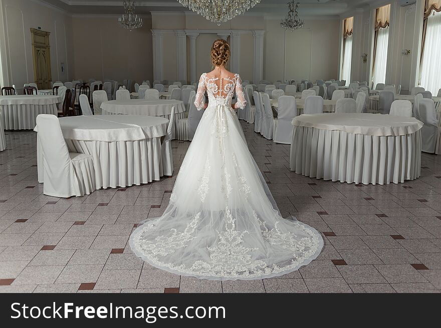 Beautiful Bride In A Wedding Dress In A Luxurious White Room With A Large Chandelier