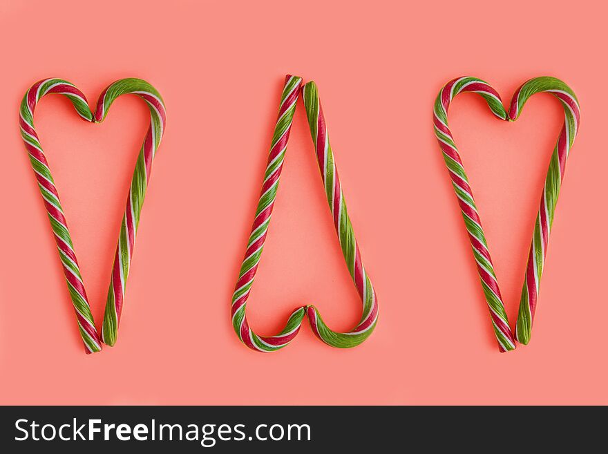 Christmas candy canes shaped heart on coral background. Color of the 2019 year