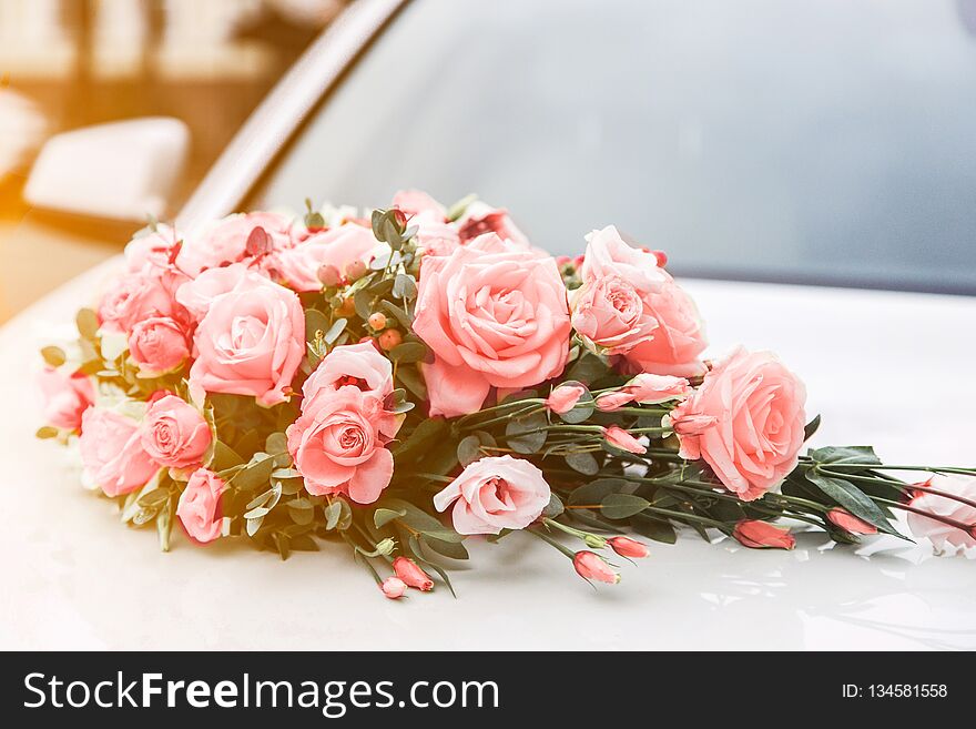Beautiful wedding bouquet of roses on the hood of a car. living coral