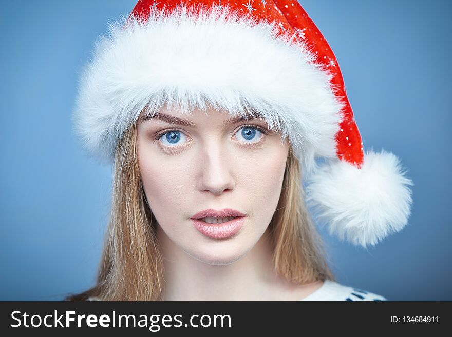 Closeup portrait of a woman wearing Santa hat, looking at camera