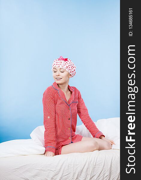 Funny happy woman after shower wearing pink pajamas and dotted bathing cap sitting on bed. Funny happy woman after shower wearing pink pajamas and dotted bathing cap sitting on bed