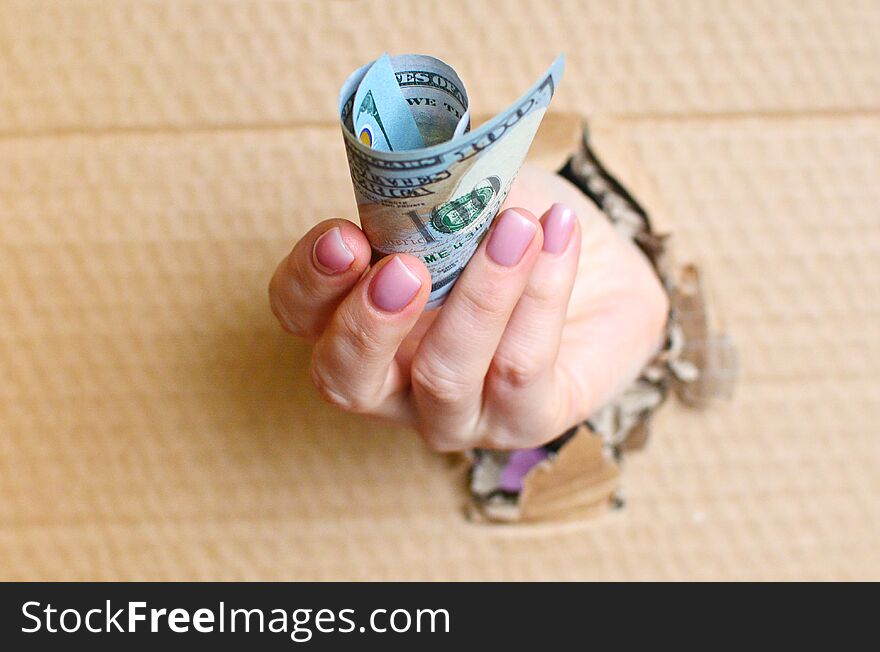 Bribe or payment concept. Giving hand with dollars through the hole.