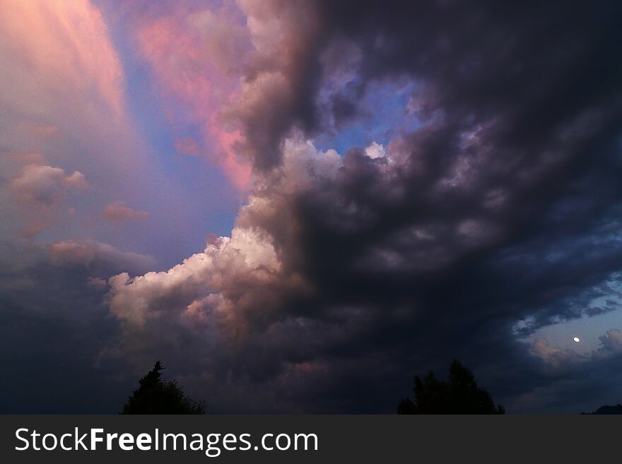 A sunset with coloured and dark clouds. Sundown with thunderclouds