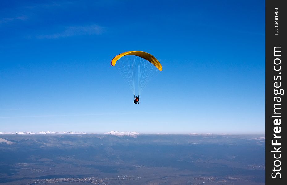 Paragliding in Bulgaria over the mountains against clear blue sky. Paragliding in Bulgaria over the mountains against clear blue sky