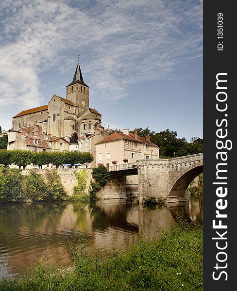 Medieval Church and Buildings in an Historic Town in France viewed from the Banks of a tranquil River.