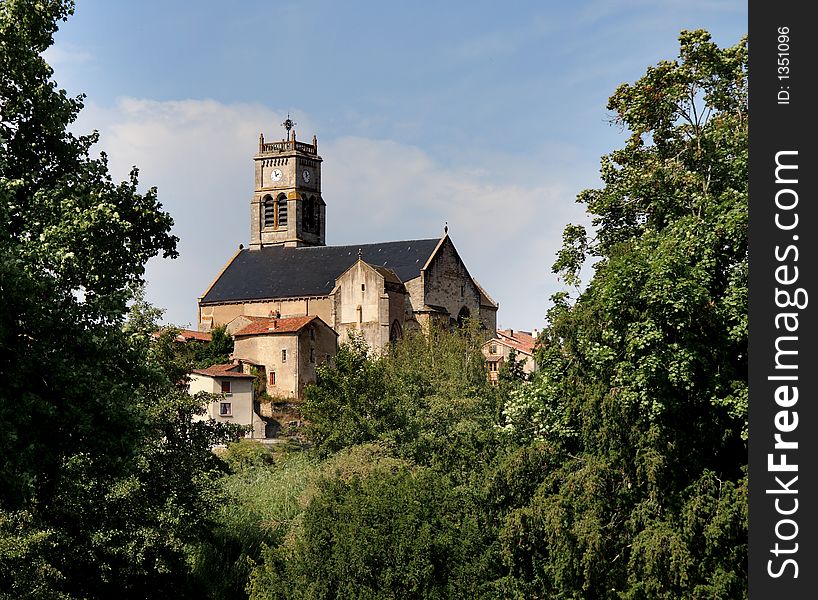 Hilltop medieval Church in Rural France viewed between trees.