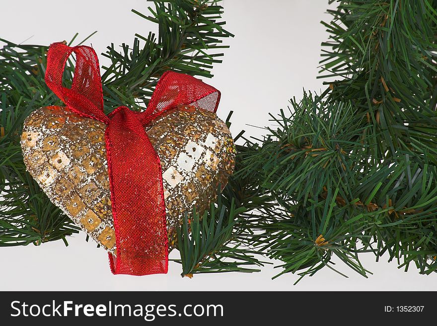 Christmas decoration gold heart with red ribbon on the pine with white background