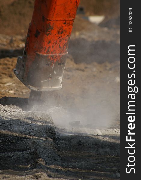 Hydraulic construction punch breaking up an asphalt roadway.