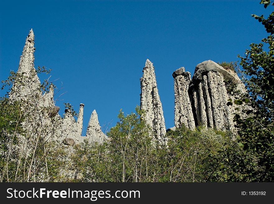 The Demoiselles CoiffÃ©es (approximate translation: young ladies with fancy hair or nice hat) is a striking set of narrowly-tapered rock columns standing along the top of a crumbly rock ridge. Each column is topped with a large rock balanced neatly on the tip, helping to protect the demoiselle from complete erosion. The Demoiselles CoiffÃ©es (approximate translation: young ladies with fancy hair or nice hat) is a striking set of narrowly-tapered rock columns standing along the top of a crumbly rock ridge. Each column is topped with a large rock balanced neatly on the tip, helping to protect the demoiselle from complete erosion.