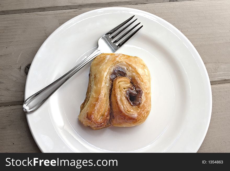 Warm cinnamon roll on white plate with fork