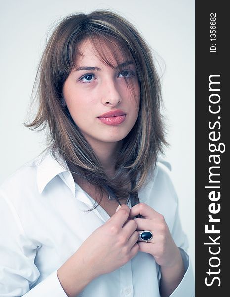 Portrait of a beautiful young girl wearing a white shirt and holding her hair with both hands. Portrait of a beautiful young girl wearing a white shirt and holding her hair with both hands