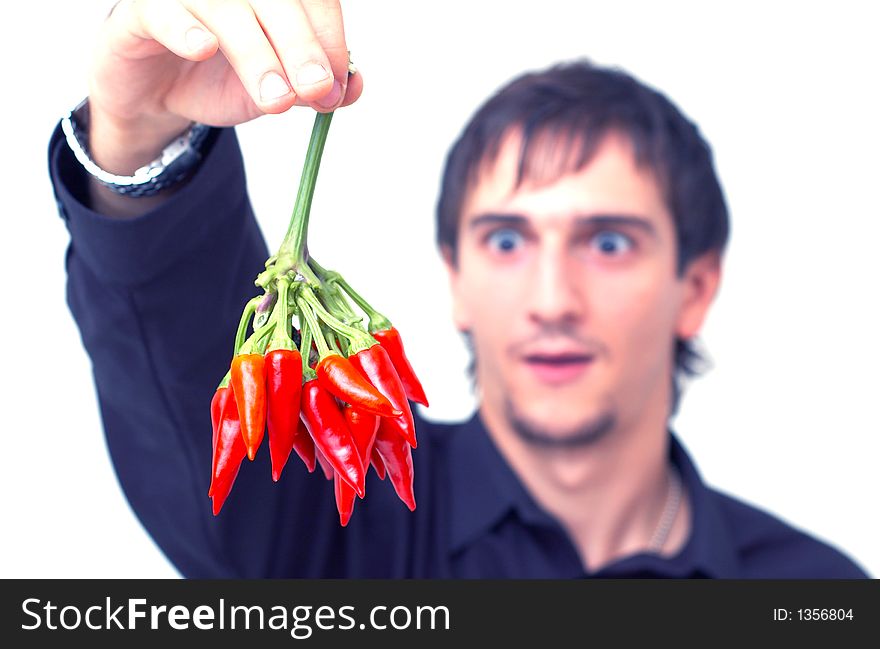 Young boy with black shirt holding a buch of red chilli peppers and having a funny expression; white background. Young boy with black shirt holding a buch of red chilli peppers and having a funny expression; white background