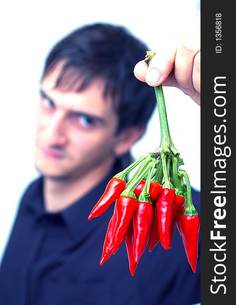 Young boy with black shirt holding a buch of red chilli peppers and having a funny expression; white background. Young boy with black shirt holding a buch of red chilli peppers and having a funny expression; white background