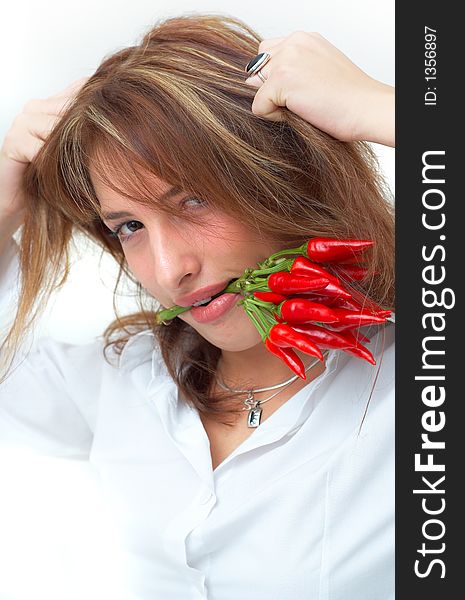 Portrait of a beautiful young girl holding a bunch of red chilli peppers in her mouth and pulling on her hair. Portrait of a beautiful young girl holding a bunch of red chilli peppers in her mouth and pulling on her hair