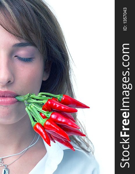 Portrait of a beautiful young girl holding a bunch of red chilli peppers in her mouth; white background. Portrait of a beautiful young girl holding a bunch of red chilli peppers in her mouth; white background