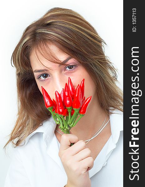 Portrait of a beautiful young girl holding a bunch of red chilli peppers in her mouth; white background. Portrait of a beautiful young girl holding a bunch of red chilli peppers in her mouth; white background