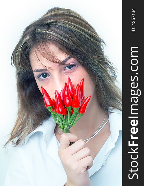 Portrait of a beautiful young girl holding a bunch of red chilli peppers in her mouth; white background. Portrait of a beautiful young girl holding a bunch of red chilli peppers in her mouth; white background