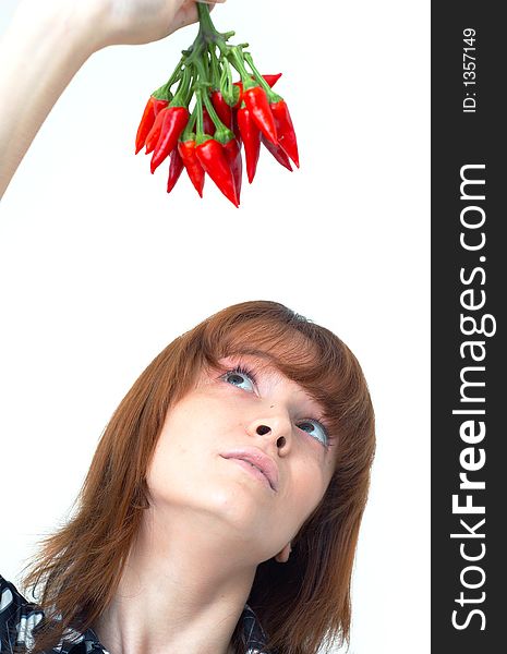 Portrait of a beautiful young girl holding a bunch of red chilli peppers over her head and looking at them; white background. Portrait of a beautiful young girl holding a bunch of red chilli peppers over her head and looking at them; white background