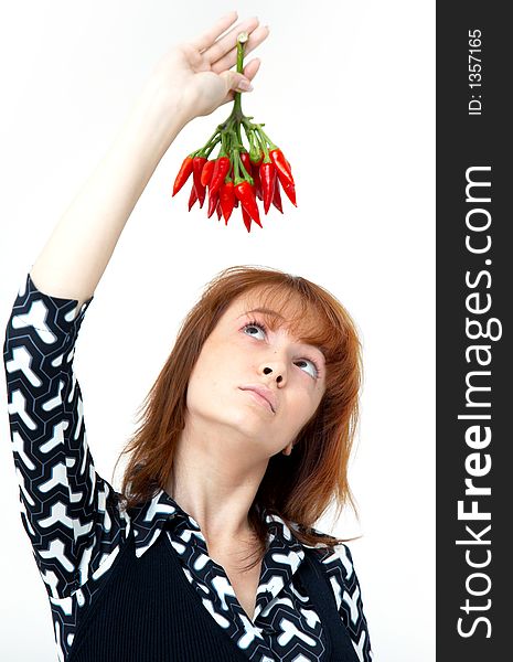 Portrait of a beautiful young girl holding a bunch of red chilli peppers over her head and looking at them; white background. Portrait of a beautiful young girl holding a bunch of red chilli peppers over her head and looking at them; white background