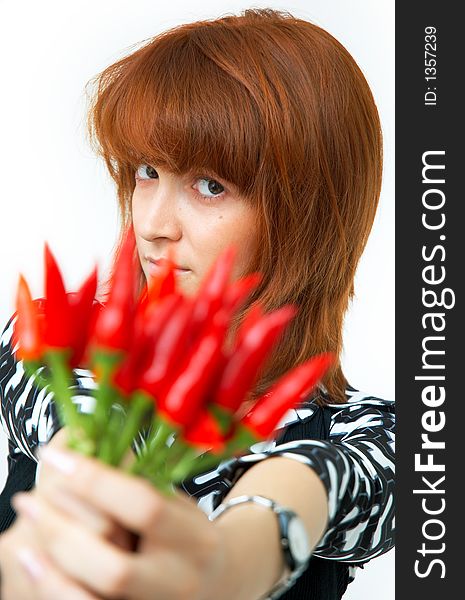 Portrait of a beautiful young girl holding a bunch of red chilli peppers over her head and looking at them; white background. Portrait of a beautiful young girl holding a bunch of red chilli peppers over her head and looking at them; white background
