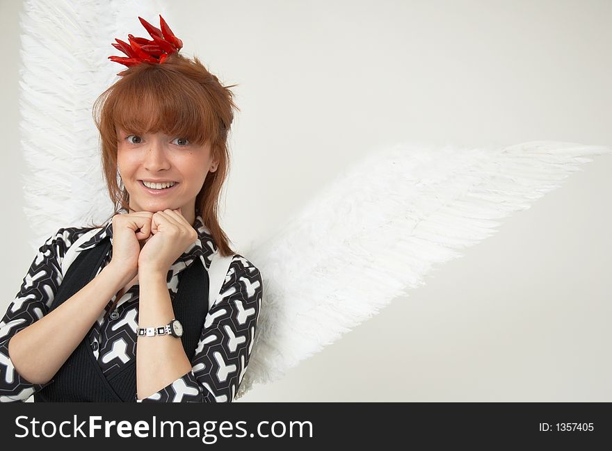 Portrait of a beautiful girl with angel wings and a bunch of red chilli peppers as a acessory for the hair. Portrait of a beautiful girl with angel wings and a bunch of red chilli peppers as a acessory for the hair