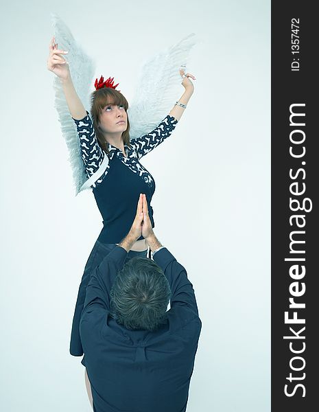 Man hands reaching a beautiful redhead girl with angel wings and a bunch of red chilli peppers as an accesory for the hair. Man hands reaching a beautiful redhead girl with angel wings and a bunch of red chilli peppers as an accesory for the hair