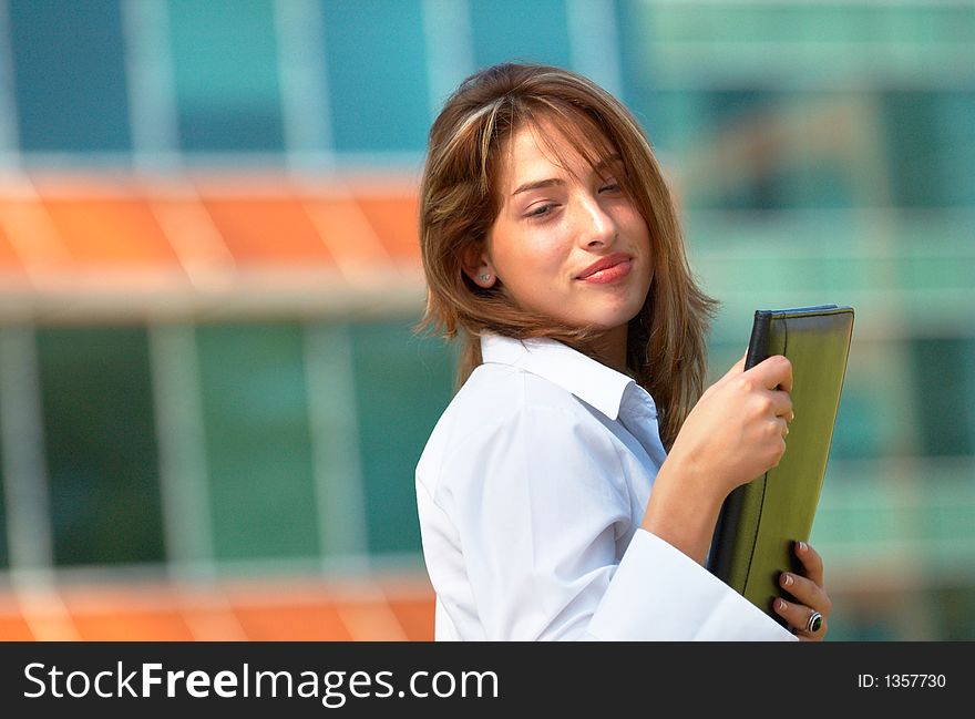 Portrait of a beautiful young girl with casual clothes holding an agenda in her hands in front of a office buiding. Portrait of a beautiful young girl with casual clothes holding an agenda in her hands in front of a office buiding
