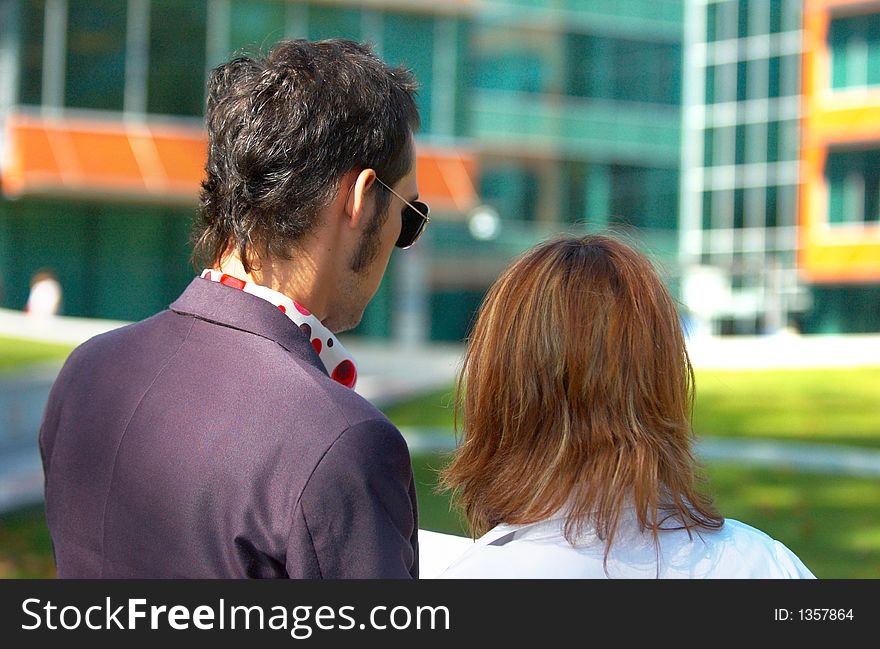 Young boy and girl checking some papers in front of an office building; business couple analising some documents. Young boy and girl checking some papers in front of an office building; business couple analising some documents