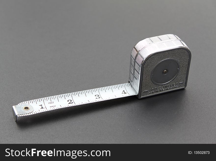 Silver tape measure extended on a grey background. Silver tape measure extended on a grey background.
