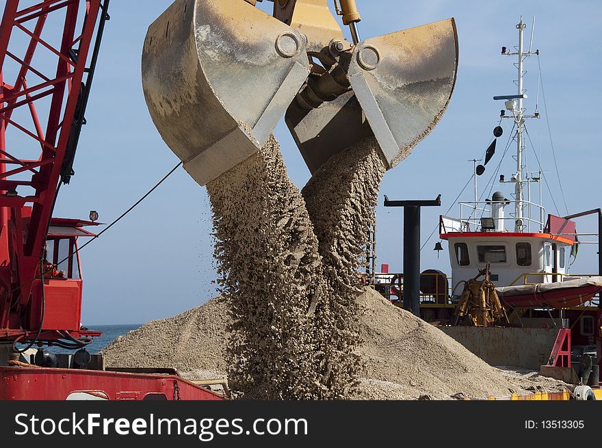 Bucket is downloading sand over the beach. Bucket is downloading sand over the beach