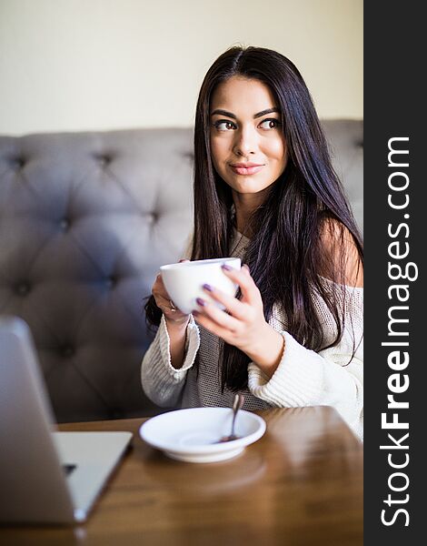 Young Beautiful Woman Drinking Coffee At Cafe Bar While Use Laptop