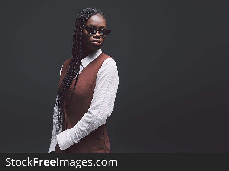 Stylish fashion young african woman in sunglasses gainst dark background