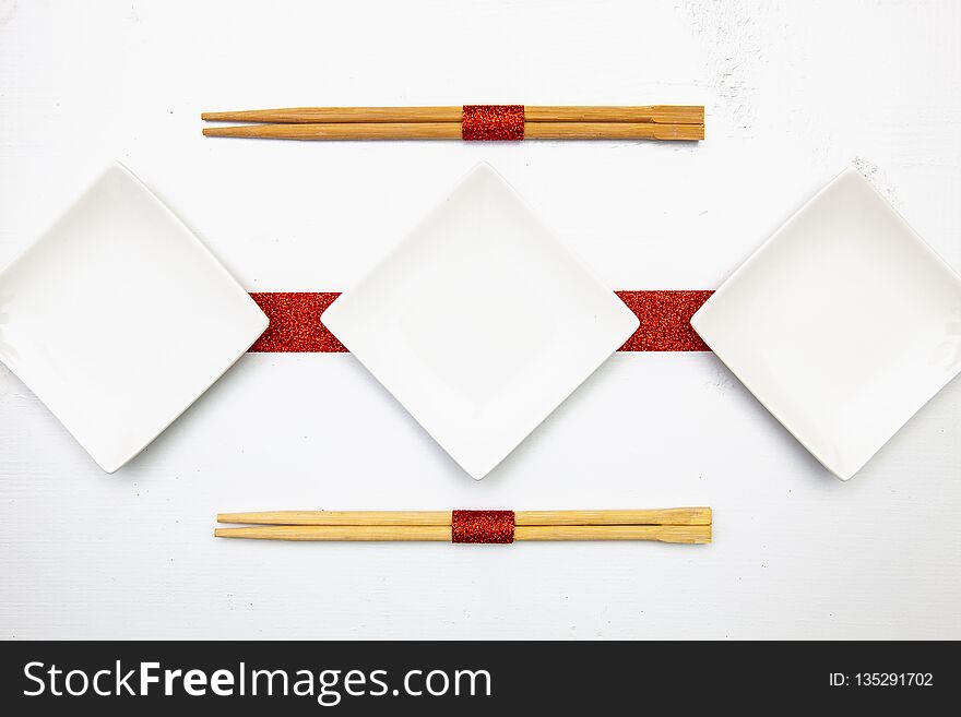 Ceramic bowls and bamboo chopsticks for sushi food with red and white decoration
