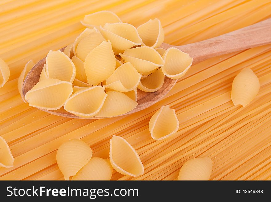Italian pasta in a wood spoon on spaghetti background
