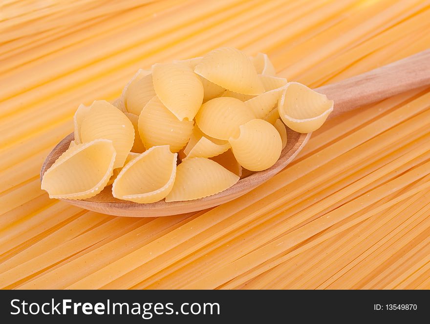 Italian pasta in a wood spoon on spaghetti background