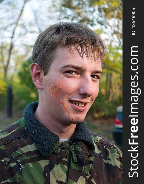 Paintball player with orange paint on the face