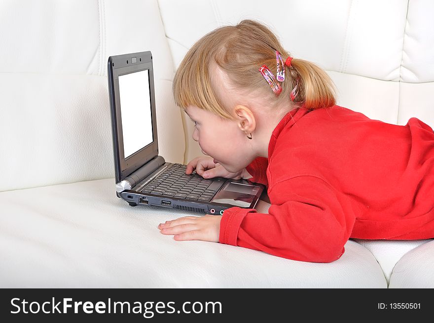 Child is laying with notebook with white screen on a sofa. Child is laying with notebook with white screen on a sofa