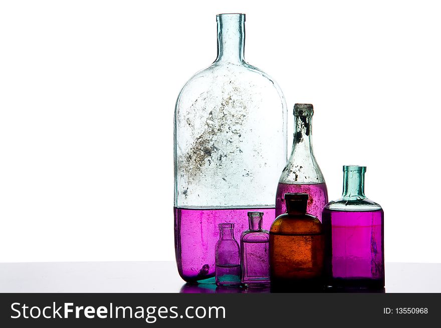 Old perfumer bottles with colorful liquid on white. Old perfumer bottles with colorful liquid on white