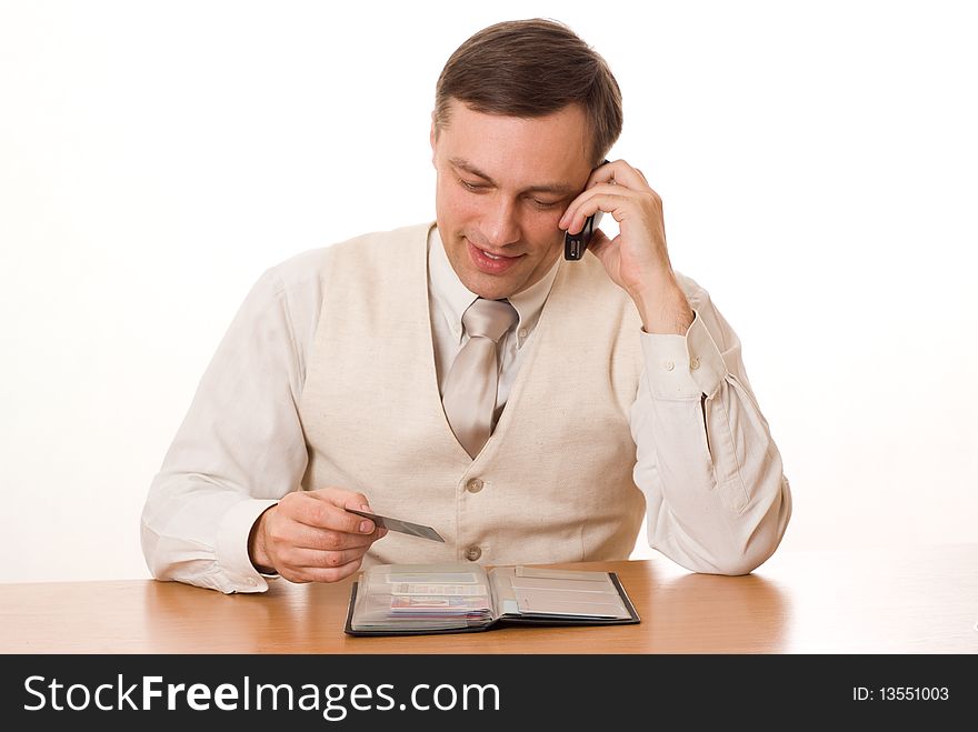 Handsome young businessman talking on the phone at the table on a white background