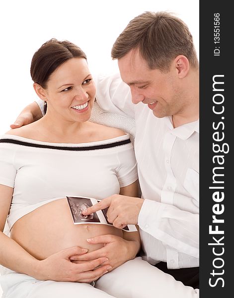 Young man with his pregnant wife sitting on a white