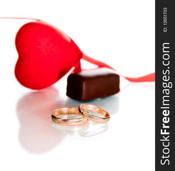 Gold rings, heart and chocolate candy isolated on white