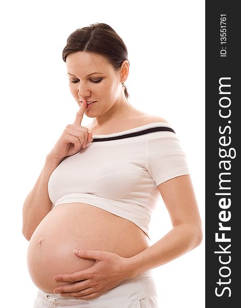 Beautiful pregnant woman looks at her stomach on a white background