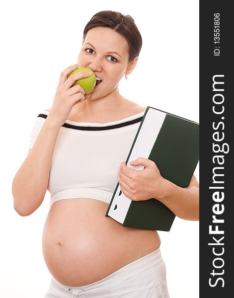 Beautiful pregnant woman holding a green book and an apple on a white
